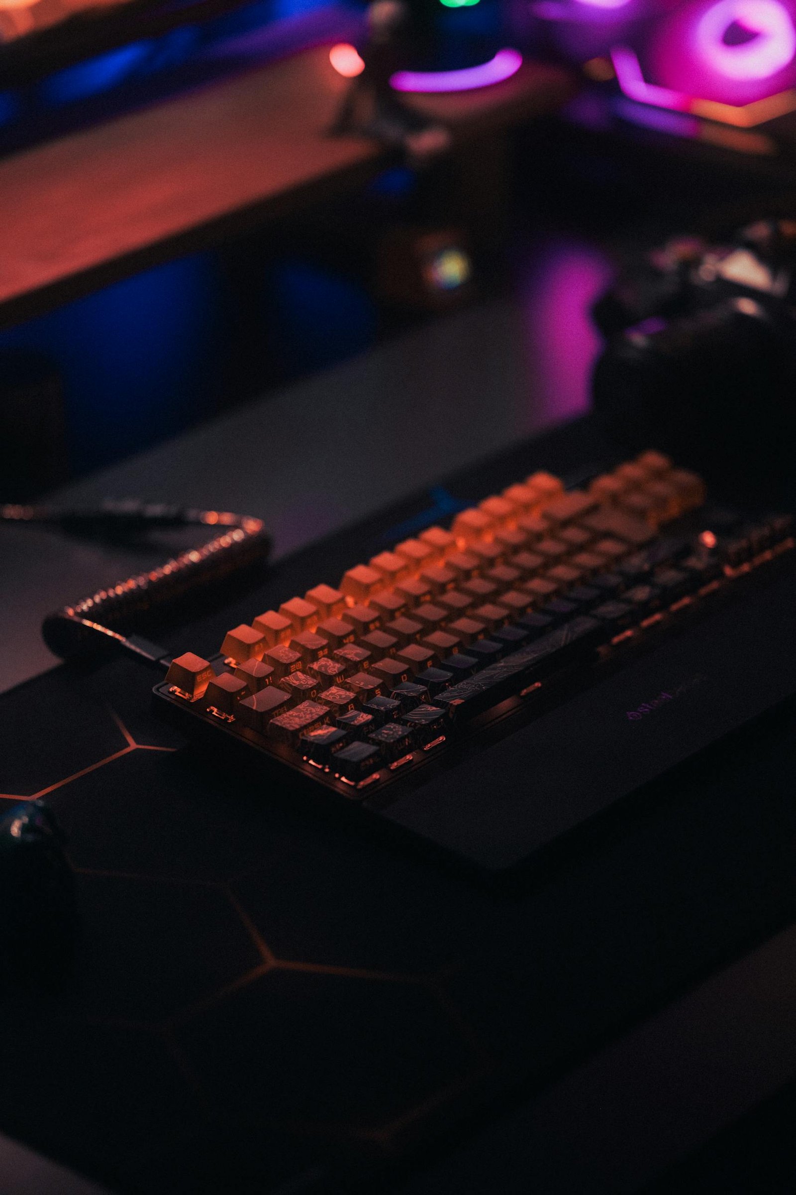 Close-up of a backlit mechanical keyboard on a dark desk, ideal for gaming setups.