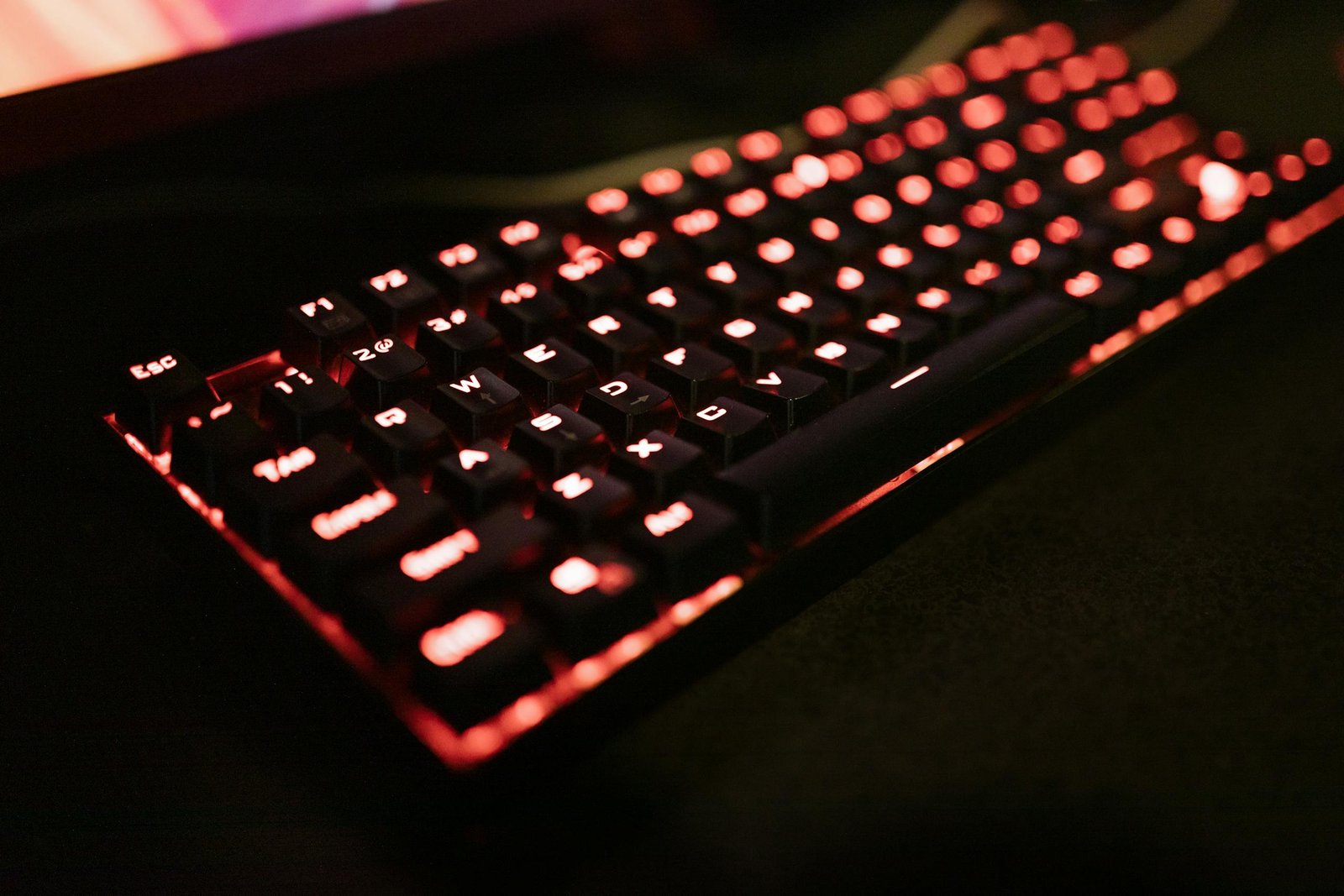 Close-up of an illuminated mechanical keyboard with red LED backlighting, perfect for gaming enthusiasts.