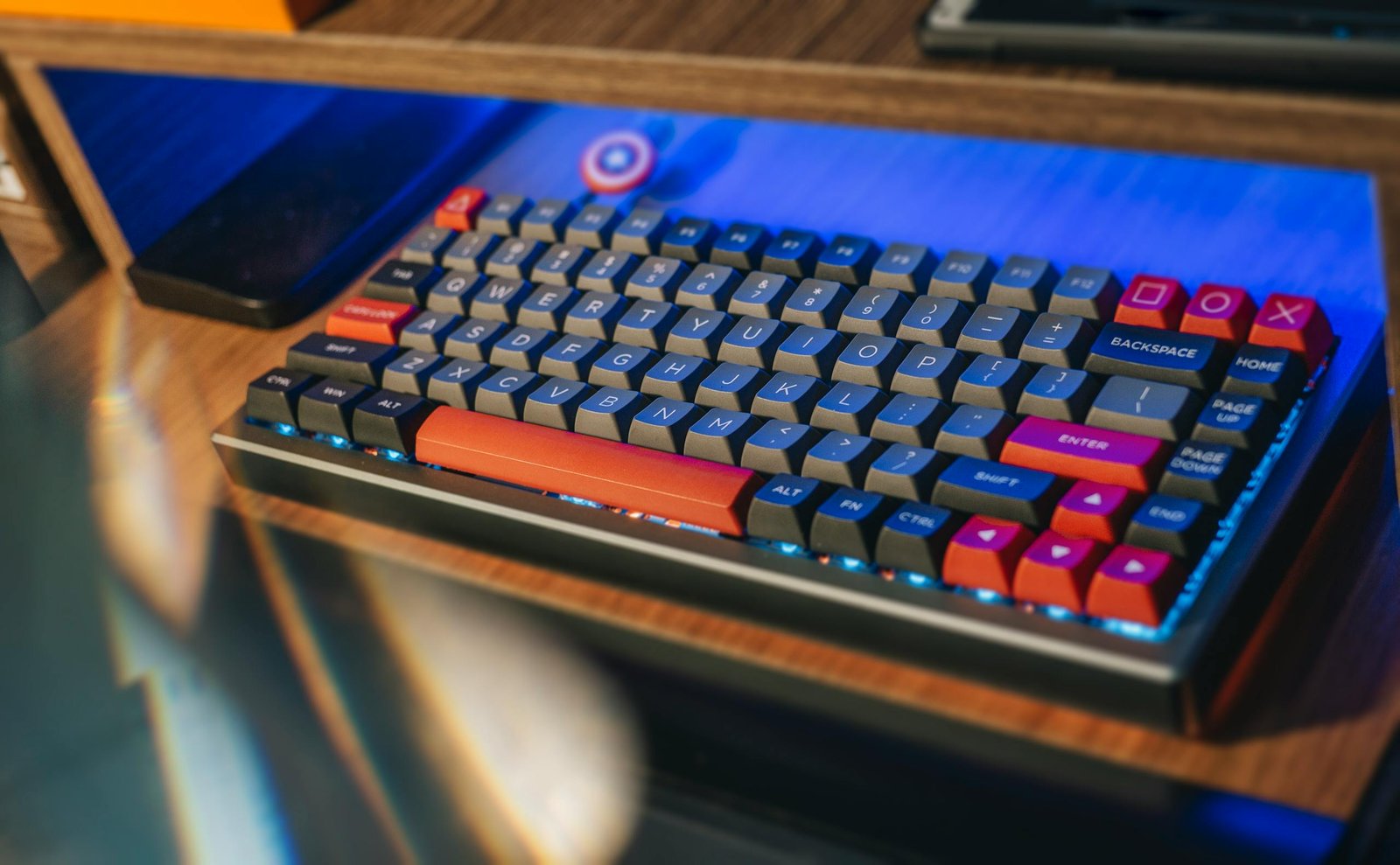 From above contemporary mechanical keyboard of black and red colors with lightning placed on wooden computer desk